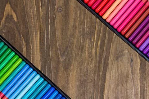 Image of the multicolored pencils, two angled rows, wooden background Stock Photos