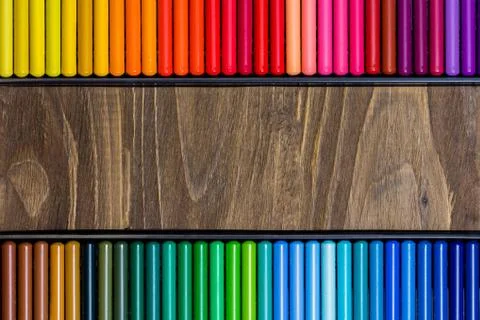 Image of the multicolored pencils, two horizontal rows, wooden background Stock Photos