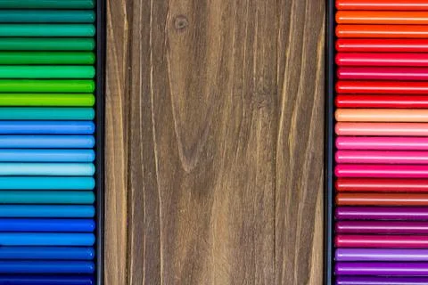 Image of the multicolored pencils, two vertical rows, wooden background Stock Photos