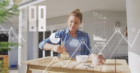 Image of multiple icons, graphs, map, caucasian woman painting wooden table at Stock Photos