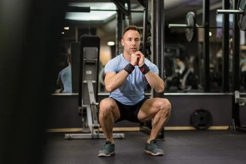 Image of a muscular man doing squads at the gym. Stock Photos