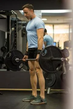 Image of a muscular man pulling a heavy barbell at the gym. Stock Photos