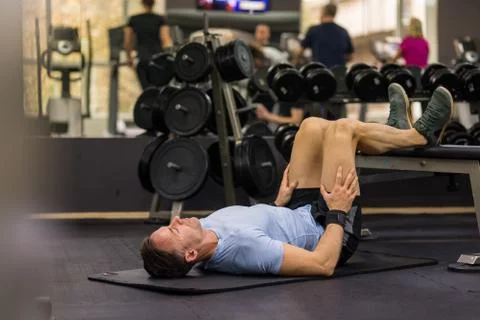 Image of a muscular man using a bench to make abdominal exercise at the gym. Stock Photos