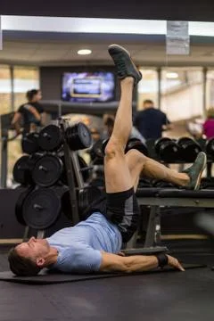 Image of a muscular man using a bench to make abdominal exercise at the gym. Stock Photos