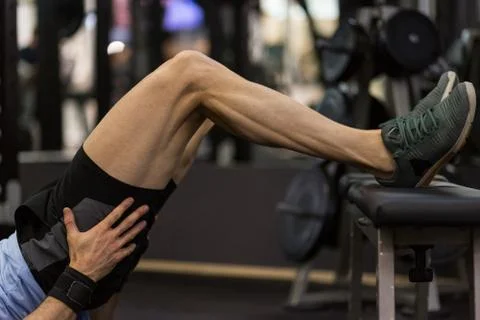 Image of a muscular man using a bench to make abdominal exercise at the gym. Stock Photos