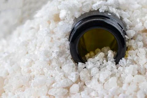 Image of the neck of an empty bottle in pieces of sea salt. Stock Photos