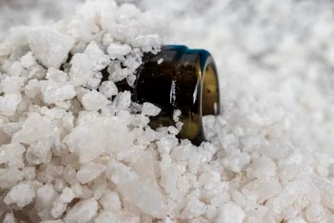 Image of the neck of an empty bottle in pieces of sea salt. Stock Photos