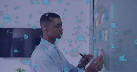 Image of network of icons over african american man sticking memo notes on board Stock Photos