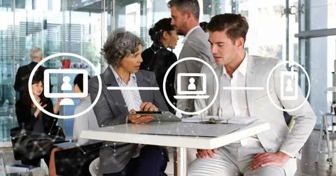 Image of network of icons over diverse businessman and businesswoman discussing Stock Photos