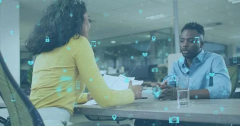 Image of network of icons over diverse man and woman discussing and shaking Stock Photos