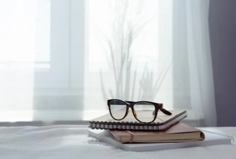 An image of a notebook and books placed in bed with glasses .blurred background Foto stock