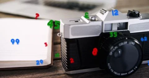 Image of numbers changing over close up of desk with camera and laptop Foto stock