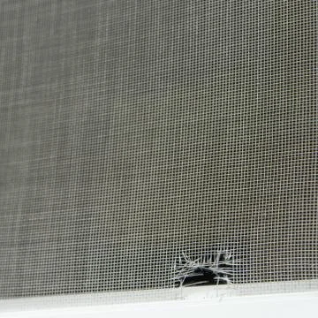 Image of an old, leaky mosquito net installed on the window Stock Photos
