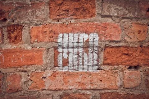 Image of a old red brick wall with a worn inscription. Stock Photos