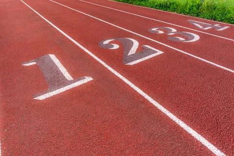 Image of an old red running track lane numbers, 1 through 4. Foto stock