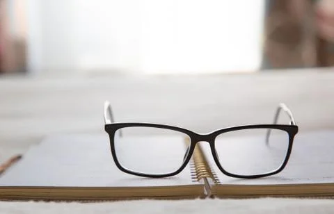 Image of an open notebook placed in bed with glasses at the top Stock Photos
