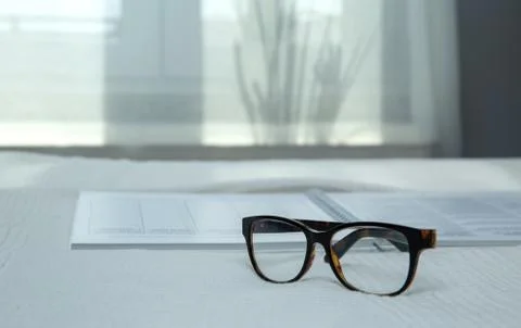 Image of an open notebook placed in bed with glasses .blurred background Stock Photos