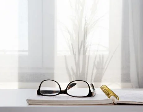 Image of an open notebook placed in bed with glasses .blurred background Stock Photos