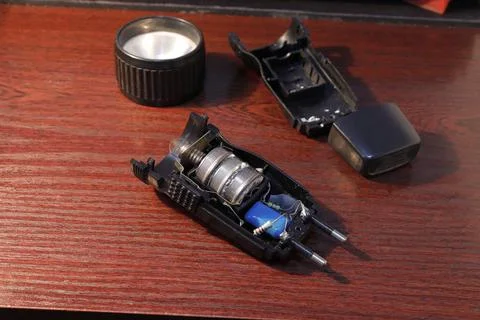 Image of an opened flashlight with old round batteries covered with oxides. Stock Photos