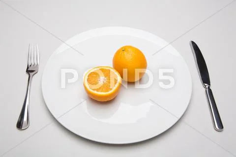 Image of oranges placed on the plate with fork and knife near by Stock-Fotos