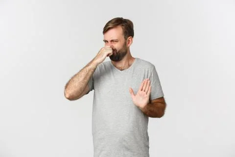 Image of an ordinary guy in gray t-shirt shut his nose, rejecting something 스톡 사진