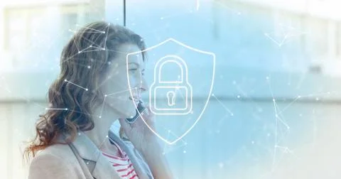 Image of padlock in shield, connected icons over caucasian woman talking on Stock Photos