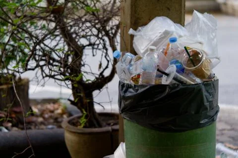 Image of plastic trash filled with trash that overflows outside. Stock Photos