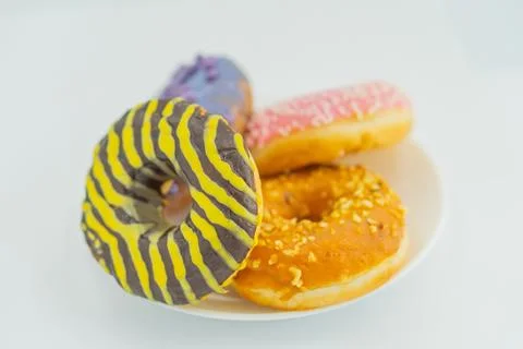 Image of a plate with three doughnuts, each decorated differently one striped Stock Photos