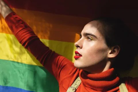 Image of profile of caucasian non-binary trans woman holding rainbow flag Stock Photos