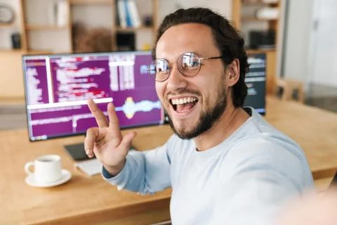 Image of programmer man gesturing peace sign while taking selfie photo Stock Photos