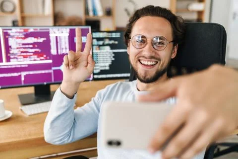 Image of programmer man gesturing peace sign while taking selfie photo Stock Photos
