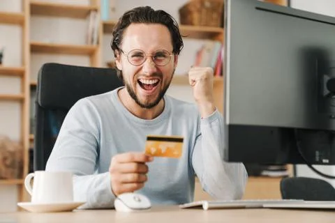 Image of programmer man making winner gesture and holding credit card Stock Photos