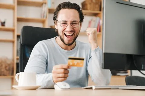 Image of programmer man making winner gesture and holding credit card Stock Photos