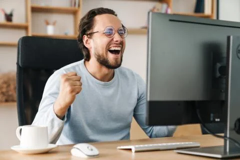 Image of programmer man making winner gesture working with computer Stock Photos