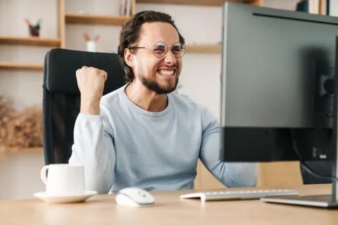 Image of programmer man making winner gesture working with computer Stock Photos