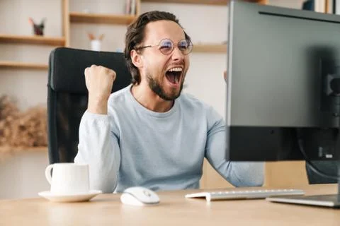 Image of programmer man making winner gesture working with computer Stock Photos