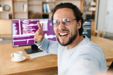 Image of programmer man pointing finger at camera while taking selfie Stock Photos