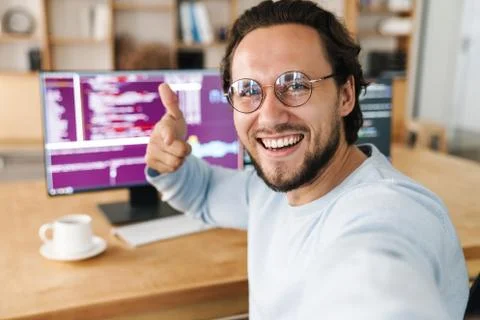 Image of programmer man pointing finger at camera while taking selfie Stock Photos