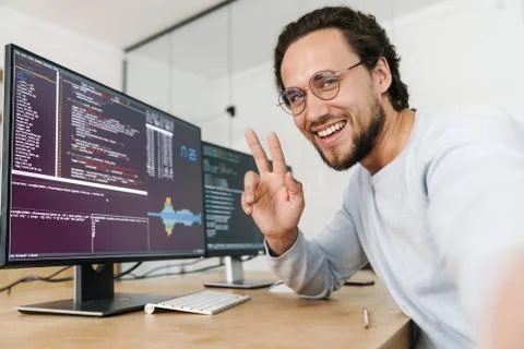 Image of programmer man showing peace sign while working with computers Stock Photos