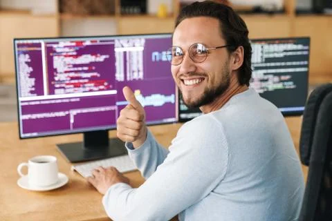 Image of programmer man showing thumb up while working with computers Stock-Fotos