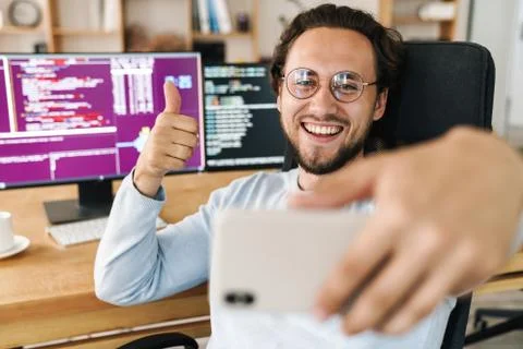 Image of programmer man showing thumb up while taking selfie on cellphone Stock Photos