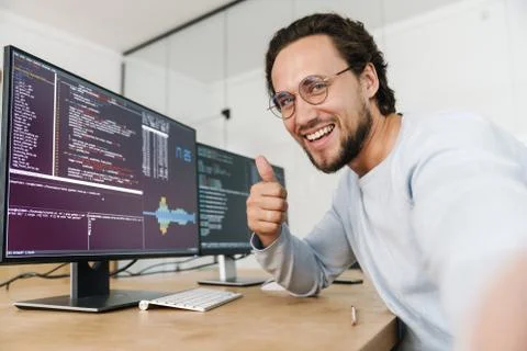 Image of programmer man showing thumb up while working with computers Stock Photos