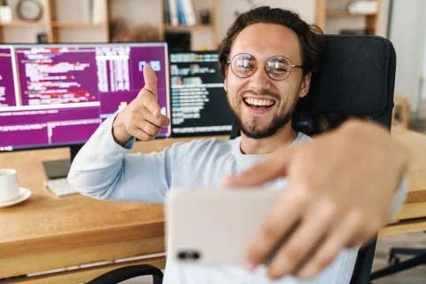 Image of programmer man taking selfie and pointing finger at cellphone Stock Photos