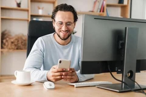 Image of programmer man using cellphone while working with computer Stock Photos