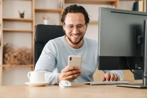 Image of programmer man using cellphone while working with computer Stock Photos