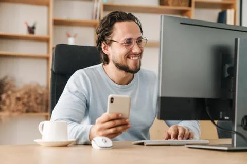 Image of programmer man using cellphone while working with computer Stock-Fotos
