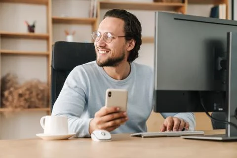 Image of programmer man using cellphone while working with computer Stock-Fotos