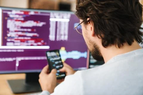 Image of programmer man using smartphone while working with computers Stock Photos