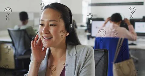 Image of question mark symbols over asian woman talking over headphones at Stock Photos