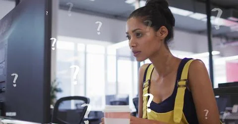 Image of question mark symbols over thoughtful biracial woman using computer at Foto stock